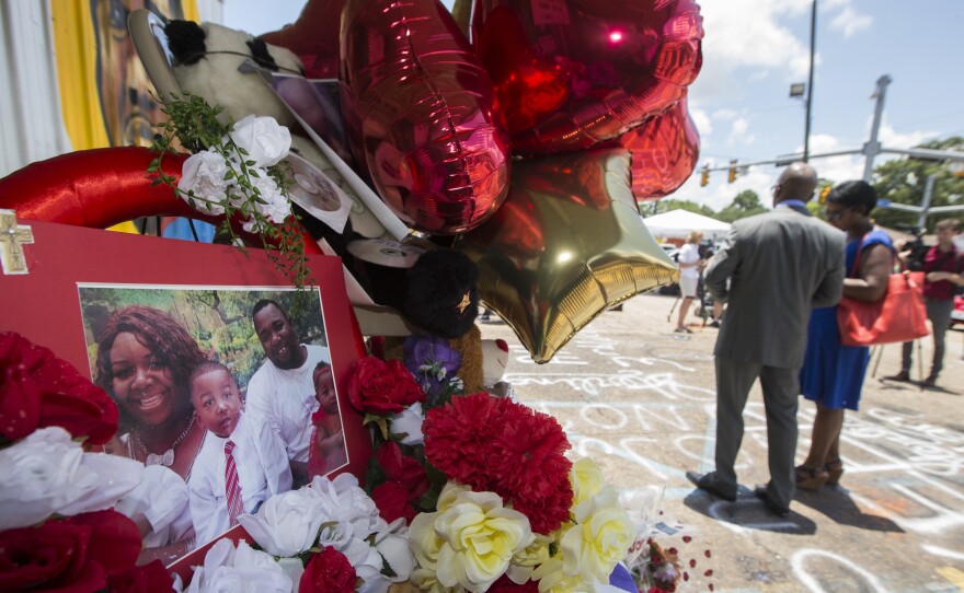 A photo of Alton Sterling and his family is displayed at a memorial outside the Triple S Mart on Thursday in Baton Rouge, La. Sterling was shot by a police officer in front of the convenience store on Tuesday.