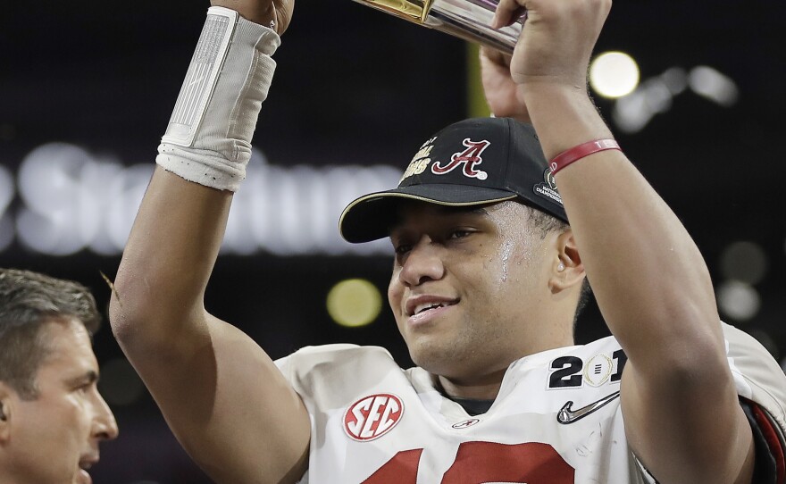 Alabama's Tua Tagovailoa holds up the championship trophy after overtime of the NCAA college football playoff championship game against Georgia, on Monday in Atlanta.