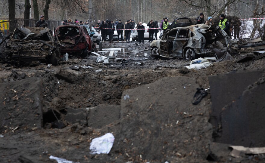 Residents stand near their apartment building, damaged during a Russian missile strike in Ukraine's capital Kyiv. Dozens were injured during the early hours of Dec. 13 after air defense systems intercepted incoming Russian ballistic targets.