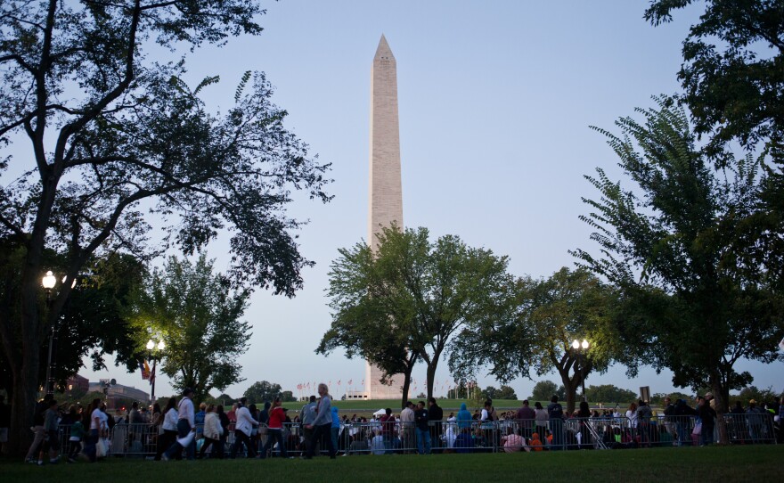 Spectators claim their spots along the papal parade route, with the Washington Monument as a backdrop.