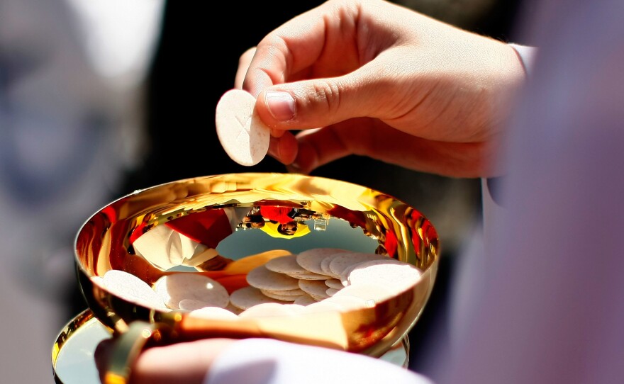 A priest holds a Holy Communion wafer in Washington, DC.