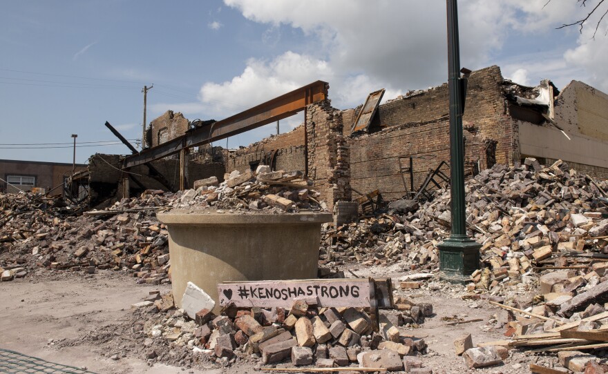 A sign stating "#KENOSHASTRONG" sits on a pile of bricks in front of a destroyed building in the Uptown neighborhood of Kenosha, WI.