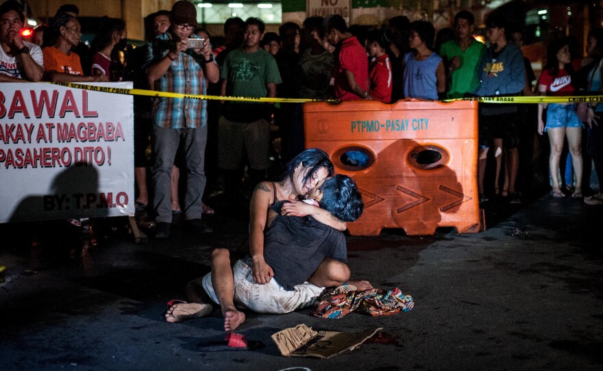 A grieving woman clutches her dead husband after armed assailants shot him in a main thoroughfare in July in Manila, Philippines. The man was accused of being a drug peddler, a claim disputed by his wife, who maintained her husband was nothing more than a pedicab driver plying his trade when he was shot in front of her.