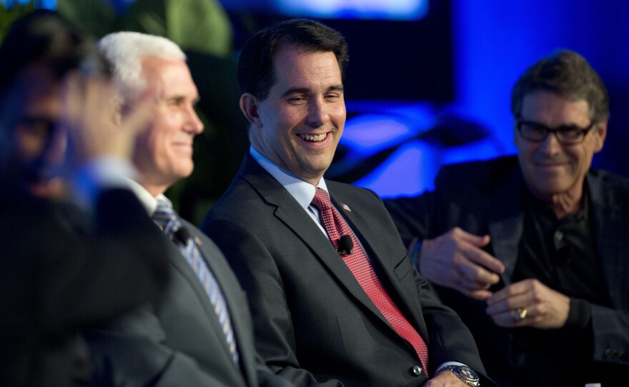 Wisconsin Gov. Scott Walker, center, talks about recent Republican party gains and the road ahead for their party as Indiana Gov. Mike Pence, left, and Texas Gov. Rick Perry listen during a news conference at the Republican Governors Association conference in Boca Raton, Fla.