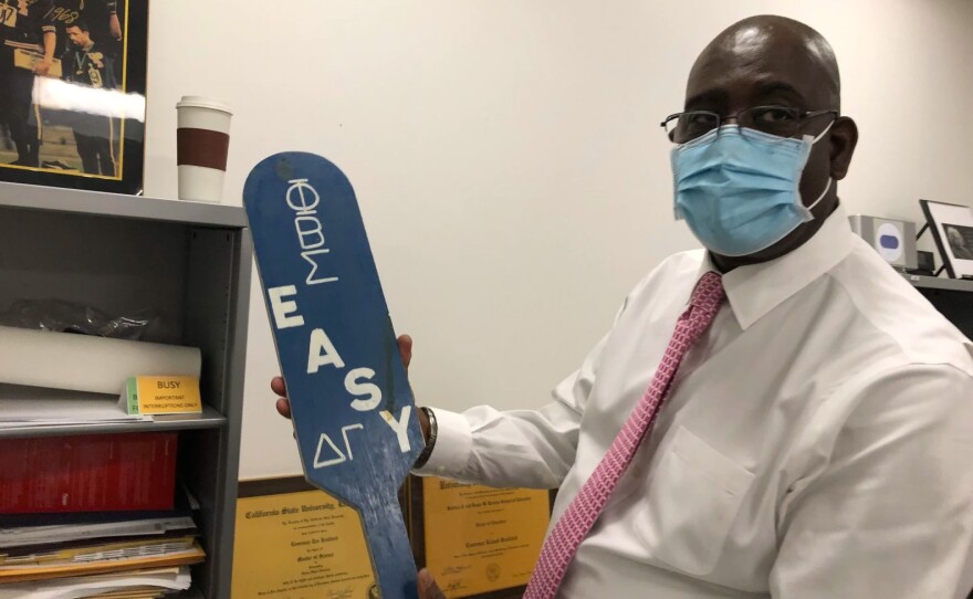 College administrator Lawrence Bradford holds a wood paddle from his college fraternity Phi Beta Sigma in this undated photo. He's seeing his son off to UC Berkeley this year.