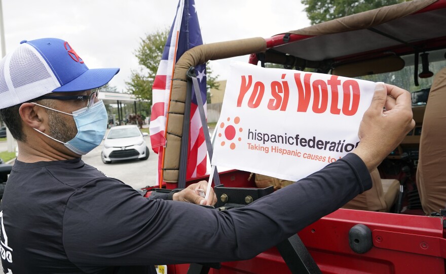 John Gimenez attaches a flag to his vehicle during an event hosted by the Hispanic Federation to encourage voting in the Latino community Sunday, Nov. 1, 2020, in Kissimmee, Fla. The Hispanic Federation is a non-partisan organization.