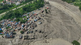 Damaged houses stand precariously near the swollen, debris-choked banks of the Trishuli River after flash floods in Nepal's Nuwakot district on Wednesday, Aug. 26, 2026.