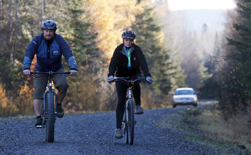 Nurse Kaci Hickox, right, and her boyfriend, Ted Wilbur are followed by a Maine State Trooper as they ride bikes on a trail near her home in Fort Kent, Maine, on Thursday.
