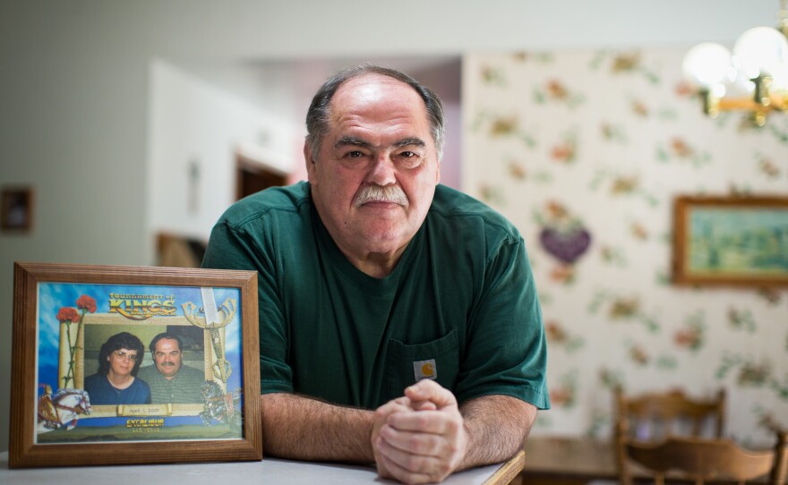 Mike Clapshaw poses with a picture of him and his wife, Deborah, in his Port Angeles, Wash., home.