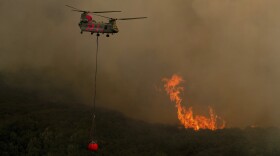 A helicopter carries water while battling the River Fire in Lakeport, Calif., on Tuesday, July 31, 2018. 