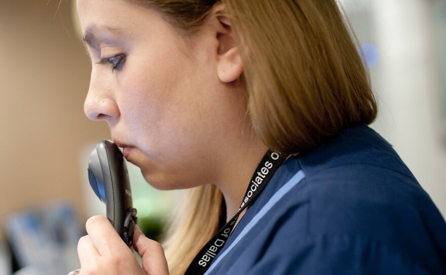 As the doctor examines a patient, medical scribe Connie Gayton records the visit using a microhone tethered to her laptop.