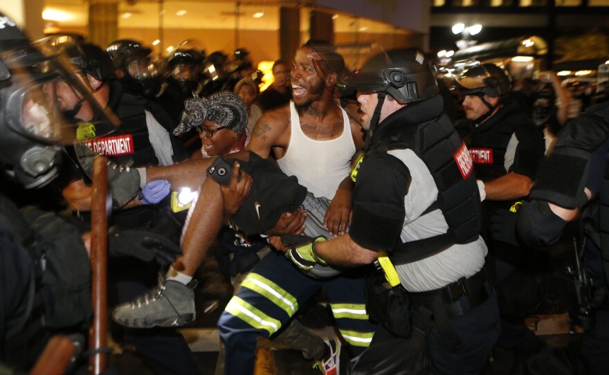 Police and protesters carry a seriously wounded protester into the parking area of the the Omni Hotel during a march on Wednesday in Charlotte, N.C. The shooting victim is on life support. Police say the protester was shot by another civilian, while many protesters blamed police for the shooting. After the shooting, the uptown protest turned into hours of violence and destruction.
