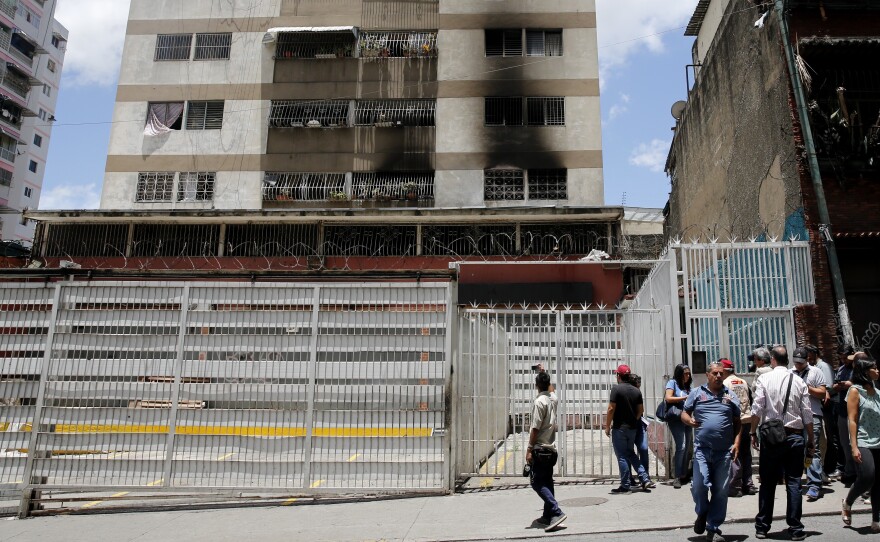 Members of the media circulate outside an apartment complex where an allegedly armed drone crashed Saturday in Caracas, interrupting President Nicolas Maduro's speech.