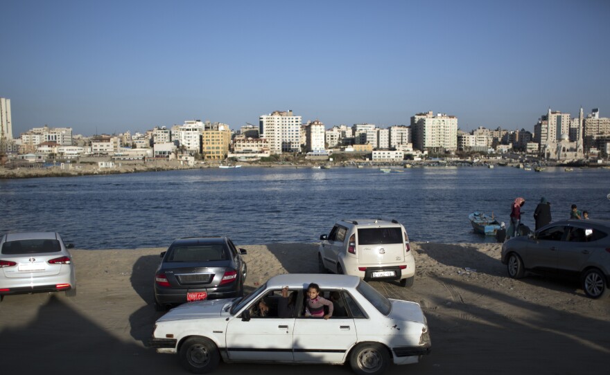 A girl appears from the window of a car driving along the beach in Gaza City.