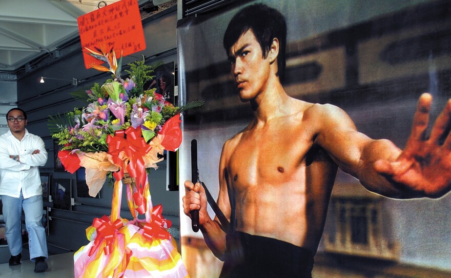 A man walks past a giant poster of kung fu legend Bruce Lee on July 16, 2003, during an exhibition at Hong Kong's Art center marking the 30th anniversary of Lee's death.