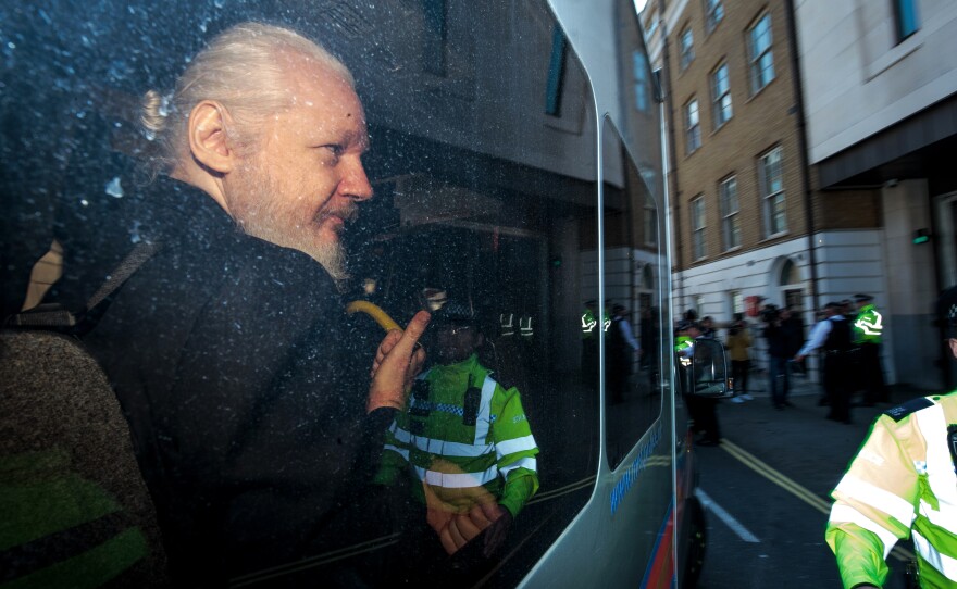 Julian Assange gestures to the media from a police vehicle on his arrival at Westminster Magistrates court on April 11, 2019 in London, England. After weeks of speculation Wikileaks founder Julian Assange was arrested by Scotland Yard Police Officers inside the Ecuadorian Embassy in Central London this morning.