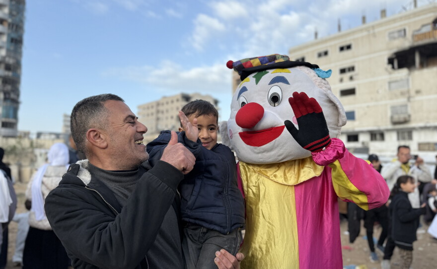 A child smiles next to a man dressed as a clown on the first day of Eid al-Fitr, celebrations that mark the end of Ramadan fasting, in Gaza City on March 20, 2026.