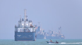 A small motorboat passes anchored vessels in the Strait of Hormuz off Bandar Abbas, Iran, Thursday, June 11, 2026.