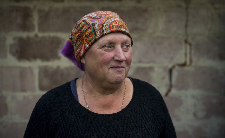 Kateryna Yurchenko, 60, stands near what remains of her lifelong home as volunteers work to clean it up in Kolychivka, seven months after it was destroyed on March 9.