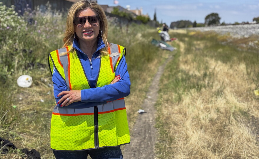 Susan Santana, president of AT&T West, stands by a path along a railroad in Hayward, Calif., where cables were cut.