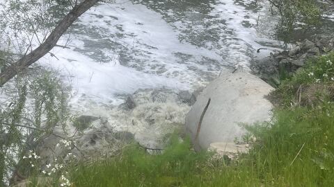 Wastewater flows out of pipe and polluted foam clouds float on top of the Tijuana River in the Nestor neighborhood of San Diego, California on April 16, 2025.