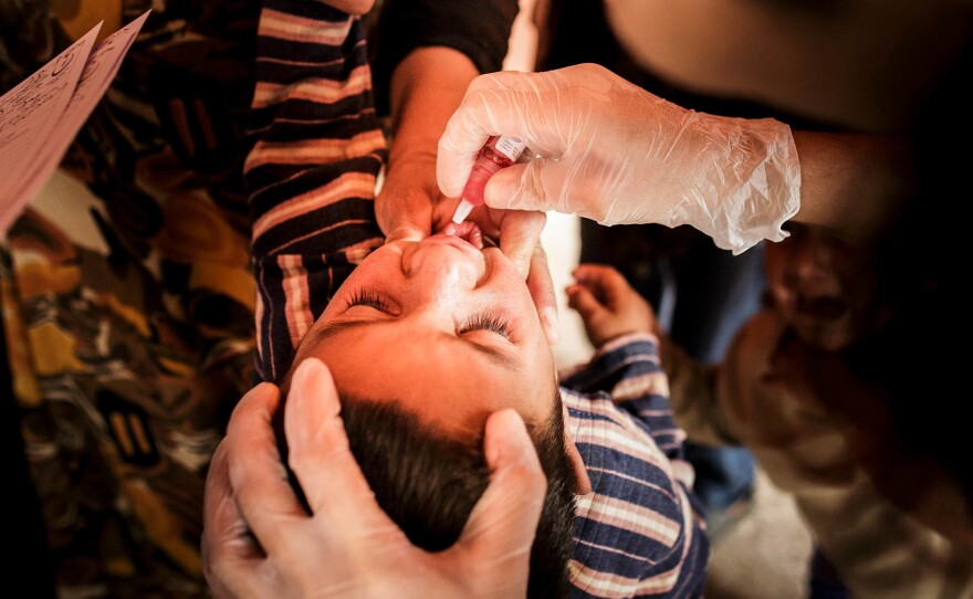 Nurses give the oral polio vaccine to a Syrian child in a refugee camp in Turkey. The oral polio vaccine used throughout most of the developing world contains a form of the virus that has been weakened in the laboratory. But it's still a live virus.