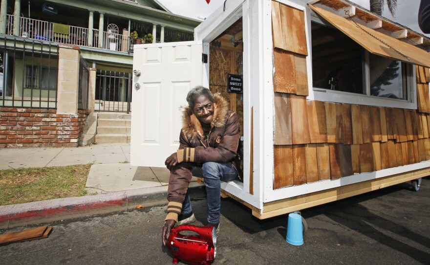 Irene "Smokie" McGhee, a woman who had been sleeping on the streets in a South Los Angeles neighborhood, listens to music in the doorway of her newly built tiny home last May.