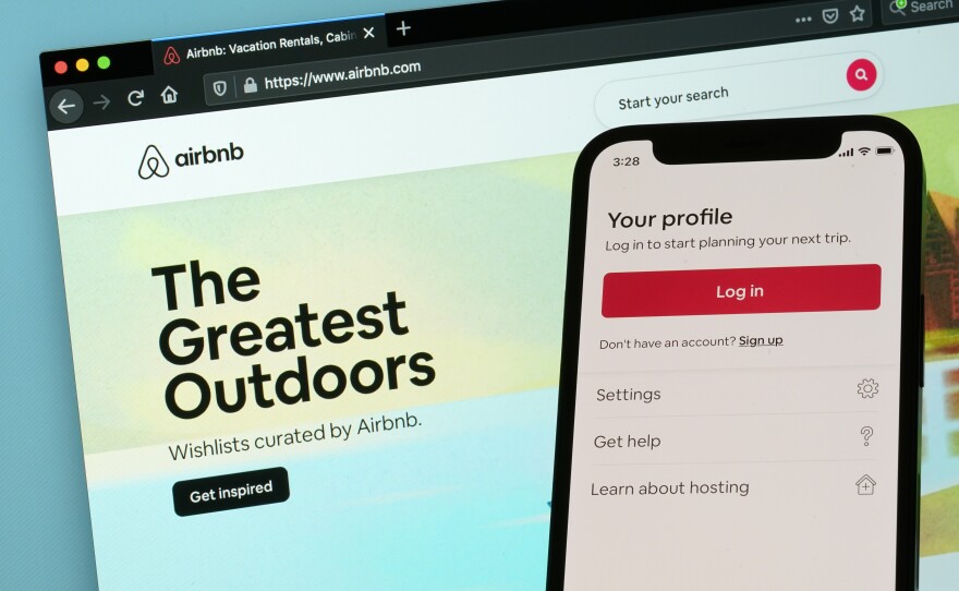 The login page for Airbnb's iPhone app is seen in front of a computer displaying Airbnb's website, Saturday, May 8, 2021, in Washington.