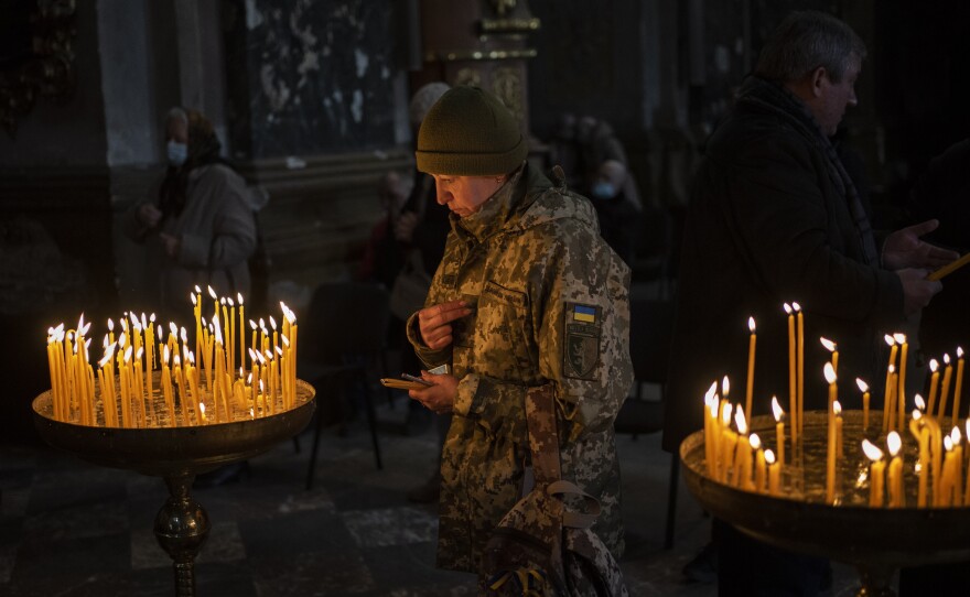 A Ukrainian woman dressed in military attire prays inside the Saints Peter and Paul Garrison Church in Lviv, in western Ukraine on Sunday.