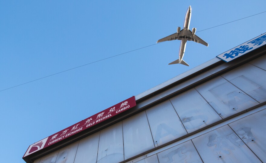 A plane flies over a commercial building in Flushing.