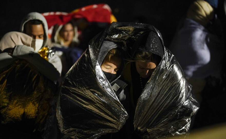 Two women from Cuba try to keep warm after crossing the border from Mexico and surrendering to authorities to apply for asylum on Thursday, Nov. 3, 2022, near Yuma, Arizona.