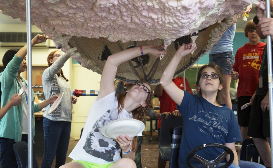 Abigail Morris (seated left) and Claire Doll paint the bottom of the brain sculpture as other students help with painting.
