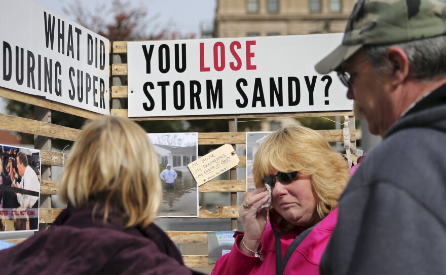 Sue Kenneally (center) wipes tears as she and other victims of Superstorm Sandy gather during a demonstration across from the statehouse in Trenton, N.J., in October 2015. More than three years after the 2012 storm, many residents are still not back in their homes.