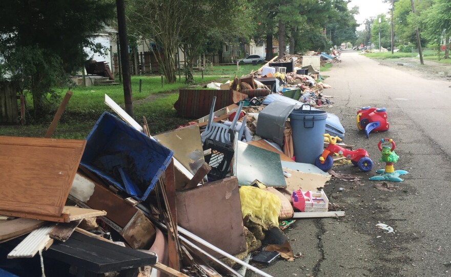 Flood-damaged debris lines a street in Baton Rouge near Claiborne Elementary, which is reopened and hosting students displaced from a nearby school.