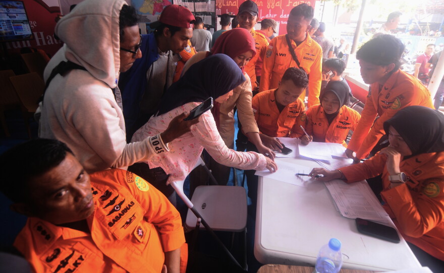 People look for the names of their family members on a passenger list after a ferry overturned in bad weather in the Java Sea, at the rescuers command center in Banjarmasin, South Kalimantan, Indonesia, Sunday, Sept. 13, 2026.