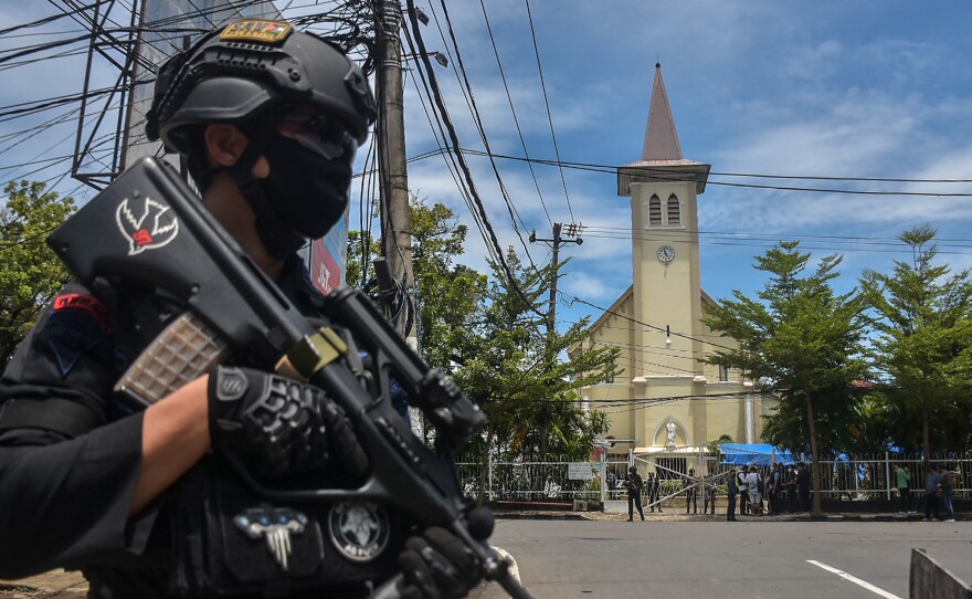 A police officer stands guard outside the Sacred Heart of Jesus Cathedral in Makassar, Indonesia, on Sunday. Two suicide bombers attacked the Roman Catholic compound, injuring at least 20 people.