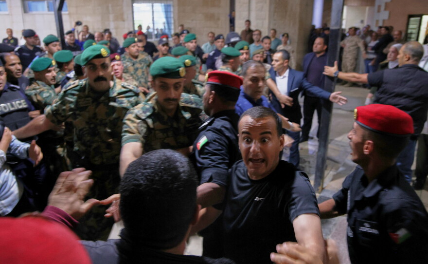 Soldiers and security officers hold back residents outside Prince Ali Military Hospital during King Abdullah II's visit to people wounded when gunmen opened fire during a funeral at a Greek Orthodox church hours earlier, in Karak, Jordan on Friday.