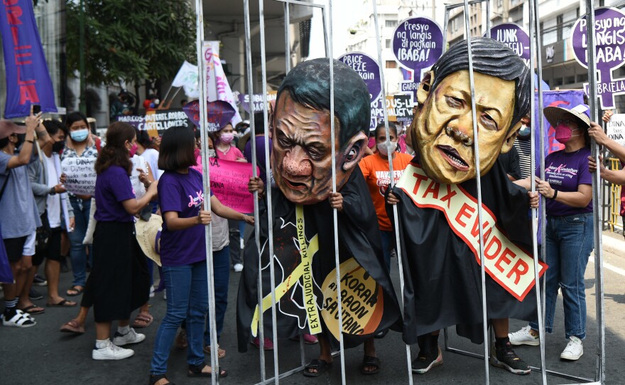 Women activists hold a makeshift prison cell with colleagues wearing masks depicting President Rodrigo Duterte (left) and Ferdinand "Bongbong" Marcos Jr. (right), son of the late dictator Ferdinand Marcos, and currently presidential aspirant for the May 9 elections, during a march to Malacanang Palace to celebrate International Women's Day in Manila last month.