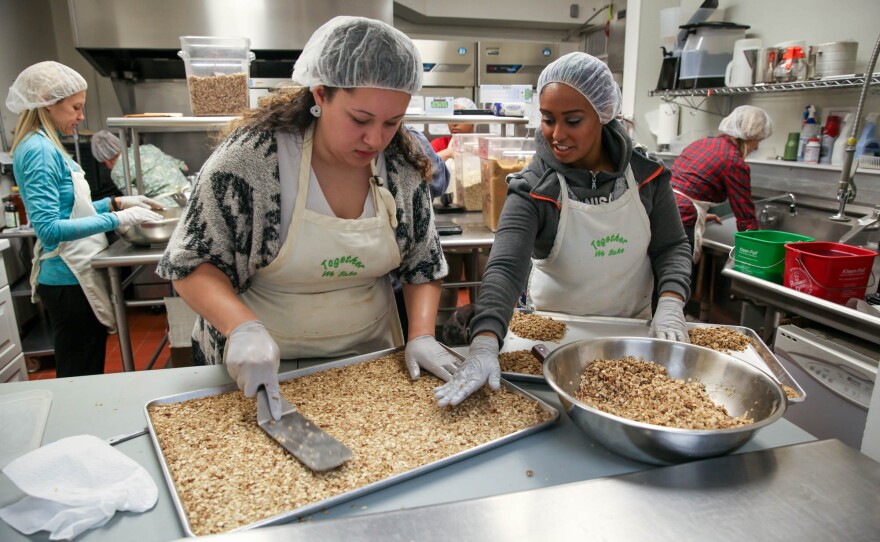 Jenyka Gassnola, an intern, and Hanna Teklu, a graduate of the program and now a program assistant, smooth out the granola before it goes to the oven to bake.