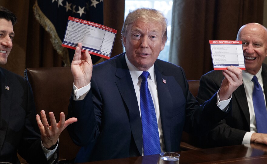 President Trump holds an example of what a new tax form may look like during a tax-policy meeting at the White House with Republican lawmakers.