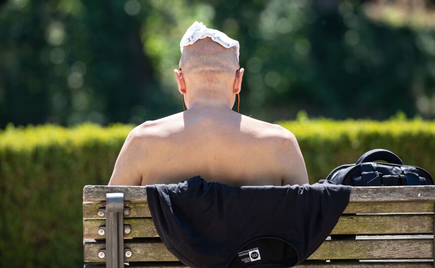 On Wednesday, a man sits shirtless on a bench along the banks of the Spree River in Berlin to keep cool.