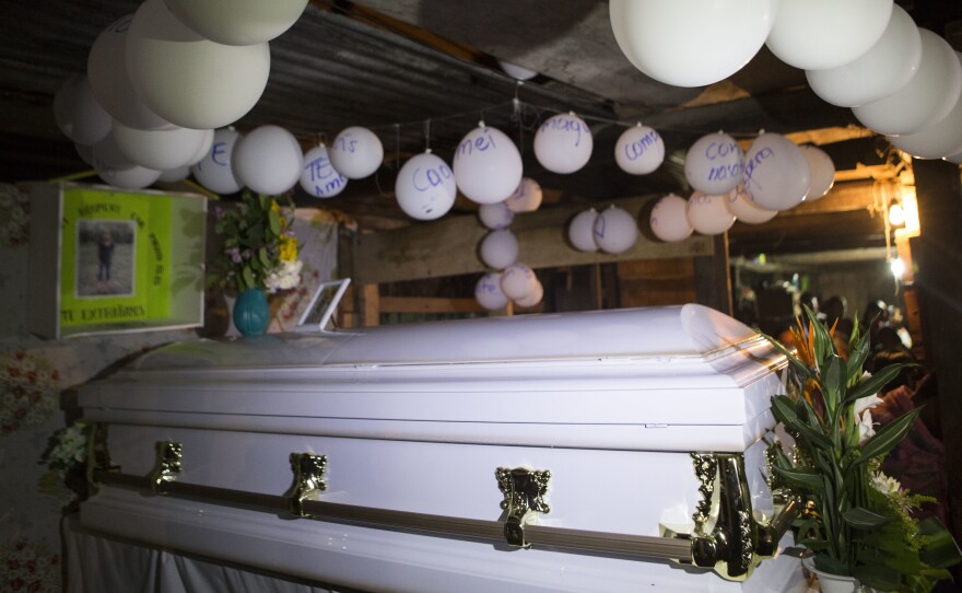 Balloons hang over the coffin that contain the remains of 7-year-old Jakelin Caal Maquin during a memorial service in her grandparents' home in San Antonio Secortez, Guatemala, Monday, Dec. 24, 2018.