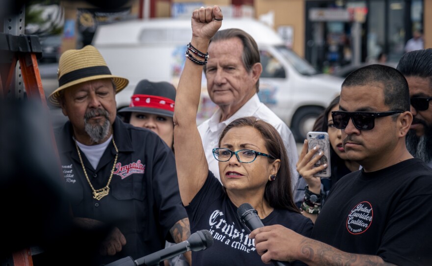 Marisa Rosales from the United Lowrider Coalition throughs her fist into the air to celebrate the removal of National City’s last “Cruising Prohibited” sign, National City, May 19, 2023.