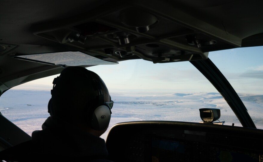 A RavnAir pilot guides a flight to Toksook Bay, Alaska, which can be seen out the window.