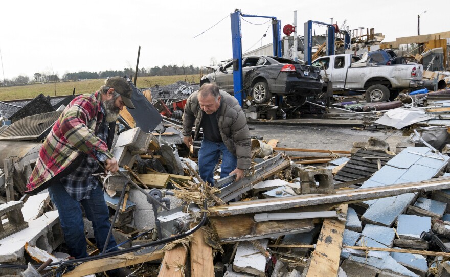 Martin Bolton (left) and shop owner Danny Wagner try to shut off a leaking gas meter on Saturday after his automobile repair shop was destroyed by a tornado in Mayfield, Ky.,