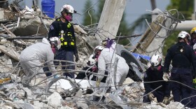 Rescue workers handle a tarp containing recovered remains at the site of the collapsed Champlain Towers South condo building, Monday, July 5, 2021, in Surfside, Fla. 