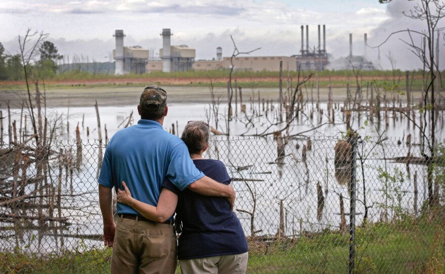 Bryant and Sherry Gobble embrace as they look from their yard across an ash pond full of dead trees toward Duke Energy's Buck Steam Station in Dukeville, on April 25, 2014. Government lawyers sought to have Duke Energy held liable for environmental damage from the leak that left the Dan River coated in hazardous coal ash, harming fish, birds and amphibians.