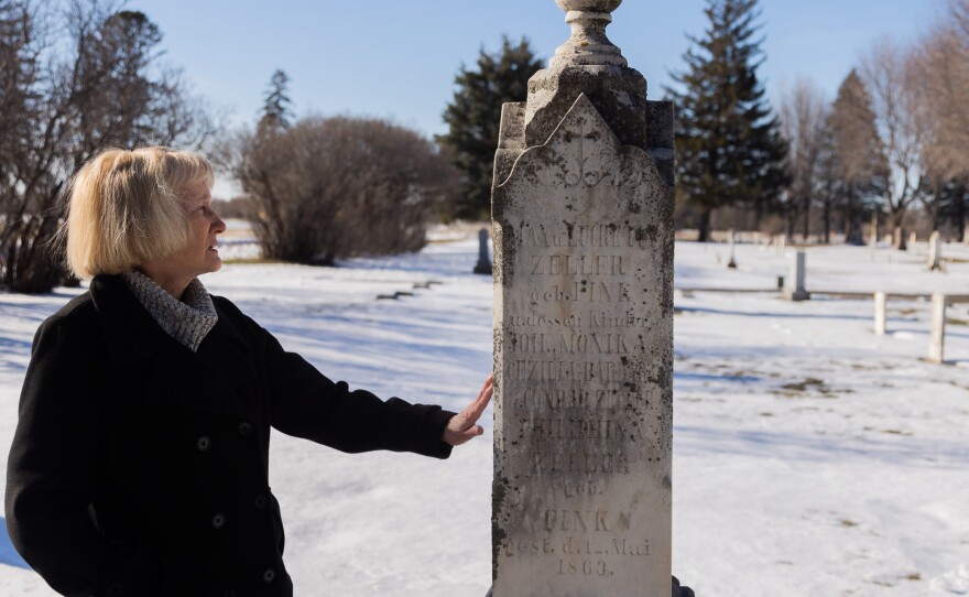 Brown County Historical Society researcher Darla Gebhard touches a grave marker at the New Ulm City Cemetery in New Ulm, Minnesota.