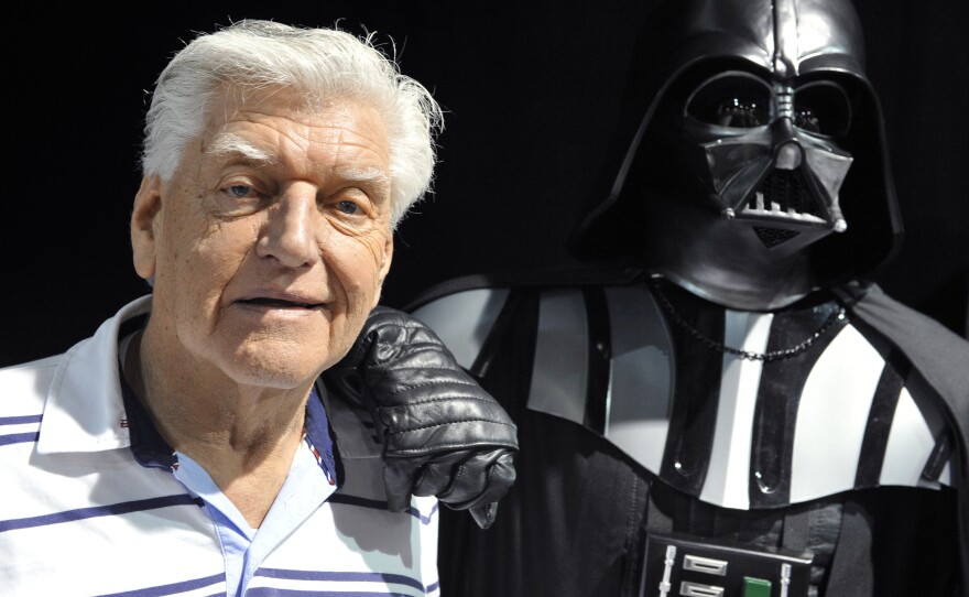 English actor David Prowse, who played Darth Vader in the first Star Wars trilogy poses with a fan dressed up in a Darth Vader costume during a Star Wars convention on April 27, 2013. Prowse died in 2020, at the age of 85.