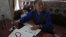 Kalsang Lhamo, a 73-year-old retired nurse, practices Tibetan calligraphy at the Chengguan District Day Care Center for the Elderly in western China's Tibet autonomous region on July 20, 2026, during a government-organized visit for foreign journalists.